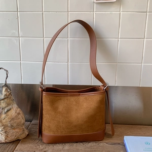 Detailed close-up of brown suede bucket bag featuring reinforced leather edges and strap
