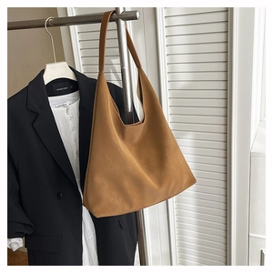 Close-up of caramel brown matte leather tote bag hanging in a minimalist studio setting