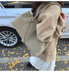 Detail of minimalist khaki suede tote bag with knotted handle in an autumn street setting