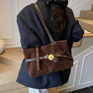 Detailed texture of dark brown suede tote bag with leather strap and decorative fringe