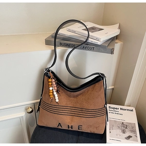 Detail of suede tote bag featuring ethnic bead charm and black leather trim accents
