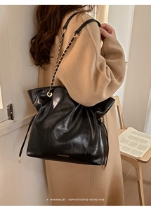 Detail of vintage black leather tote featuring gold chain strap and side drawstring accent