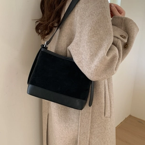 Detail of black patchwork shoulder bag showing texture contrast between suede and smooth leather