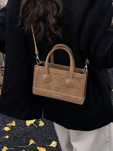 Vintage brown textured leather handbag with top handles and shoulder strap in autumn setting