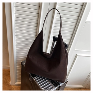 Detailed view of deep brown leather hobo tote bag on a silver suitcase for travel use