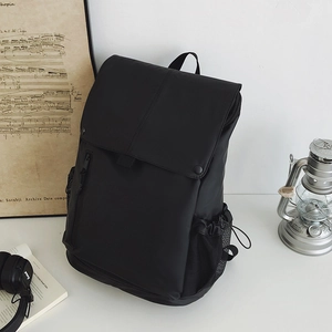 Détail d'un sac à dos noir minimaliste avec un grand compartiment et des poches latérales filet