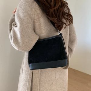 Detail showing the mixed texture of black suede and smooth leather on the shoulder bag