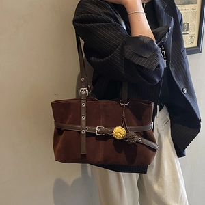 Detail of dark brown suede tote bag with leather strap accents and floral charm