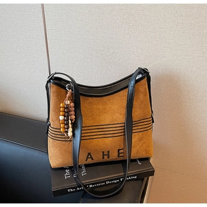 Close-up of suede tote bag featuring AHE logo and colorful beaded vintage pendant detail