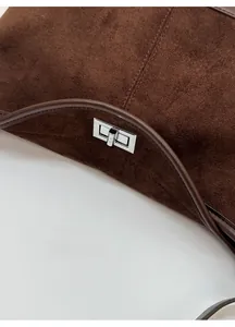 Detail of brown faux suede bag featuring a silver metal twist lock closure and smooth trim