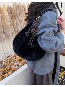 Detail of black faux fur hobo bag with metal logo and knotted charm for autumn style