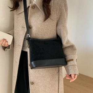 Detail showing mixed texture of black suede and matte leather on a shoulder tote bag