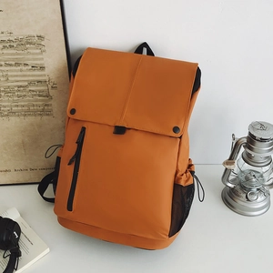 Détail d'un sac à dos extérieur orange avec rabat, boucle noire et poche en filet latérale