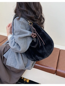 Detail of black faux fur shoulder bag featuring soft plush texture and golden metal rings