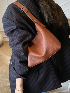 Braune Hobo-Tasche aus Leder mit verstellbarem Riemen, getragen von einem Model