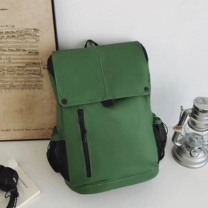 Détail du sac à dos vert herbe avec fermeture éclair noire et poche latérale en filet