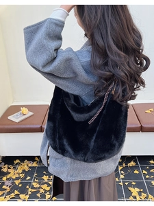 Detail view of black faux fur hobo bag with woven shoulder strap on an outdoor background
