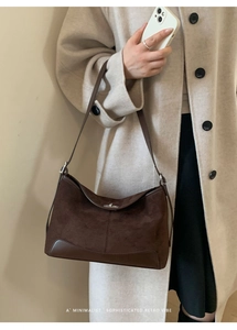 Detail of retro brown suede and leather patchwork tote with metal buckle and corner reinforcement