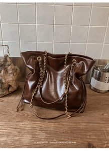 Détail macro du cuir marron foncé brillant et de la chaîne en métal d'un sac cabas rétro
