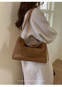 Close-up of brown suede shoulder bag featuring leather trim and retro metal buckles