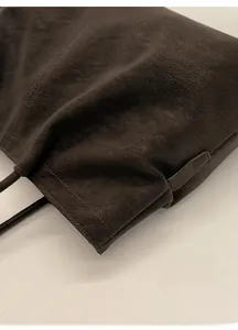 Detailed close-up of dark brown vintage faux leather tote bag with pleat design