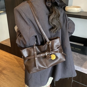 Detailed view of dark brown faux leather tote bag with stylish yellow plush pendant accessory