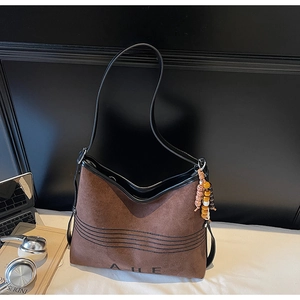 Detail of suede tote bag featuring black trim and vintage colored wood bead charm