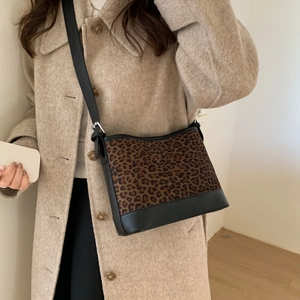Close-up of leopard print crossbody bag with black trim and adjustable silver buckle