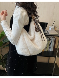 Detail showing plush white faux fur texture and brown acrylic charm on a large hobo bag