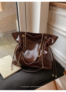 Detail of vintage dark brown tote bag in glossy oil wax leather with gold chain strap