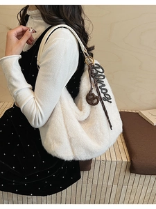 Detailed close-up of white plush tote bag with gold ring buckle and chic letter charms