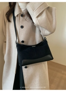 Detail of minimalist retro black frosted leather bag paired with a wool coat