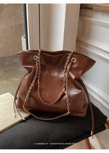 Detailed view of vintage dark brown tote bag with golden metal chain shoulder straps
