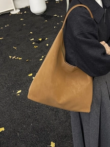 Minimalist caramel leather tote bag for women shown in a stylish outdoor street style setting