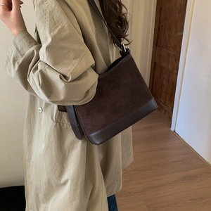 Detail of vintage brown tote bag with suede and leather contrast on khaki coat shoulder