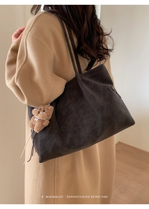 Macro shot of a dark gray frosted tote bag with a cute brown plush bear charm pendant
