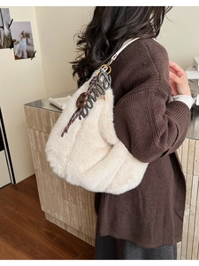 Detail of soft off-white plush shoulder bag with brown acrylic charms and fringe