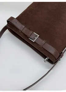 Gros plan sur un sac seau en daim marron avec boucle en cuir et fermeture éclair argent