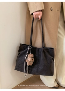 Macro view of matte suede texture on a dark grey tote bag with a cute plush bear charm