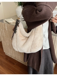 Detail of plush beige faux fur hobo bag with white leather strap and letter charm