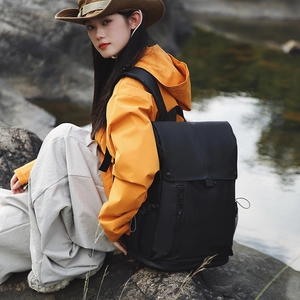Sac à dos outdoor porté par un mannequin en veste orange au bord d'un ruisseau