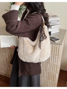 Detail of plush beige hobo bag with soft faux fur texture and dark contrast charm
