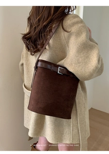 Détail du sac seau en daim marron avec décoration de ceinture en cuir et boucle argentée
