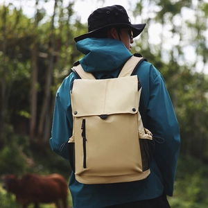 Sac à dos de voyage beige avec rabat et poches en filet porté lors d'une randonnée
