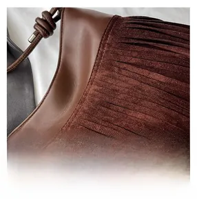Vista macro di borsa in pelle marrone con frange in camoscio e dettagli a tracolla intrecciata