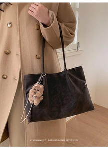 Detail of dark brown matte tote bag with removable plush dog charm on long shoulder strap