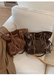 Detailed macro view of retro glossy leather tote bags with elegant chain straps and drawstrings