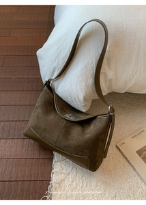 Close-up of brown suede hobo bag texture with silver metal turn-lock closure detail