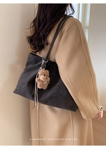 Detail view of large black matte tote bag with a cute brown plush bear charm accessory