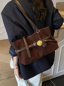 Brown suede tote bag with leather strap details and yellow flower charm on model